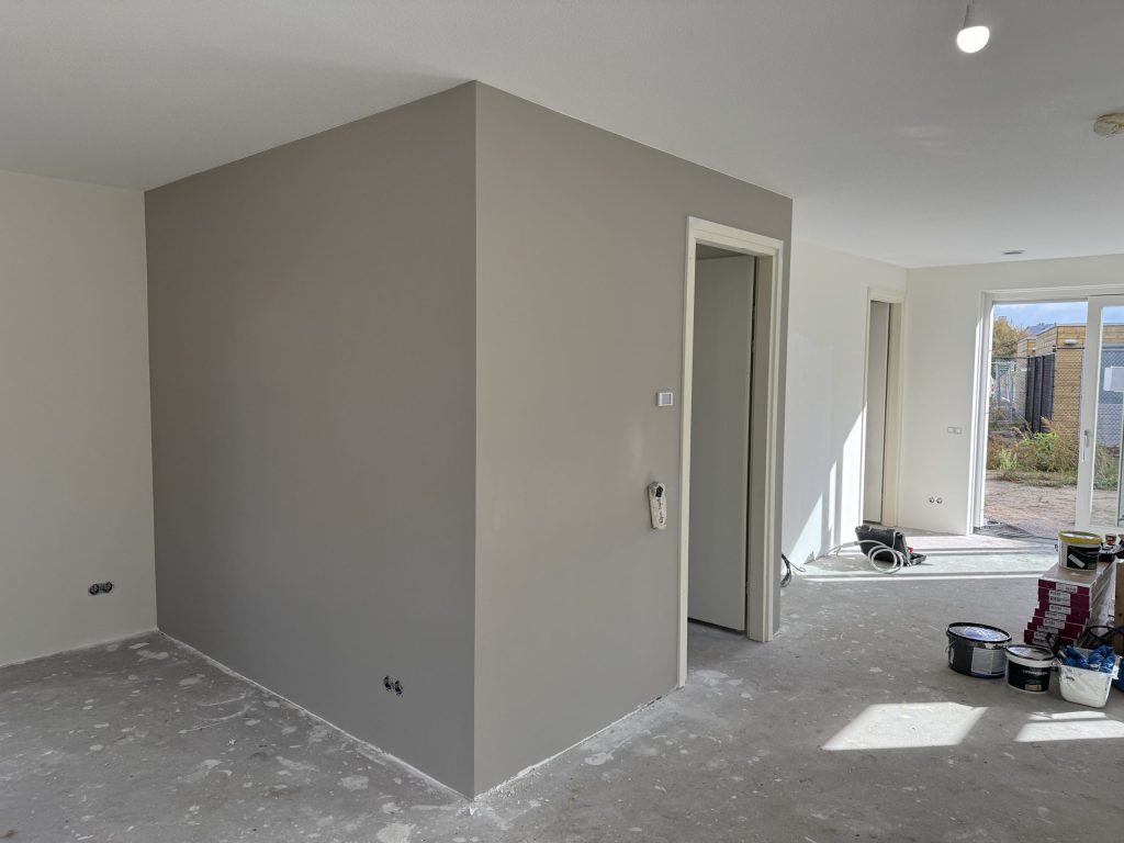 Gesausde wanden in grijs en wit in een nieuwe woning, met verfemmers op de betonvloer